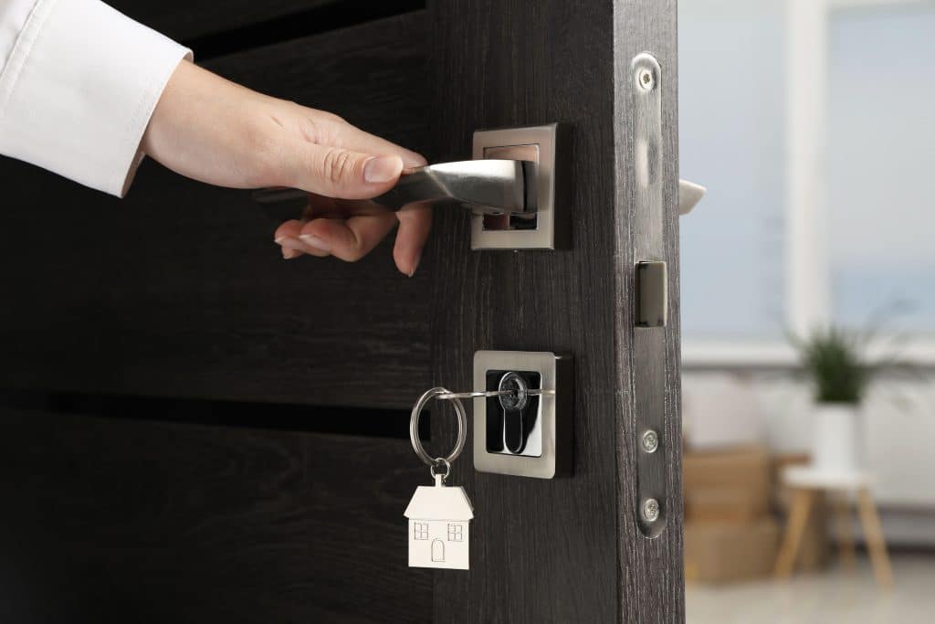 Person opening the front door with a house key, symbolising a turn-key home — a move-in ready property option popular in the Australian real estate market.